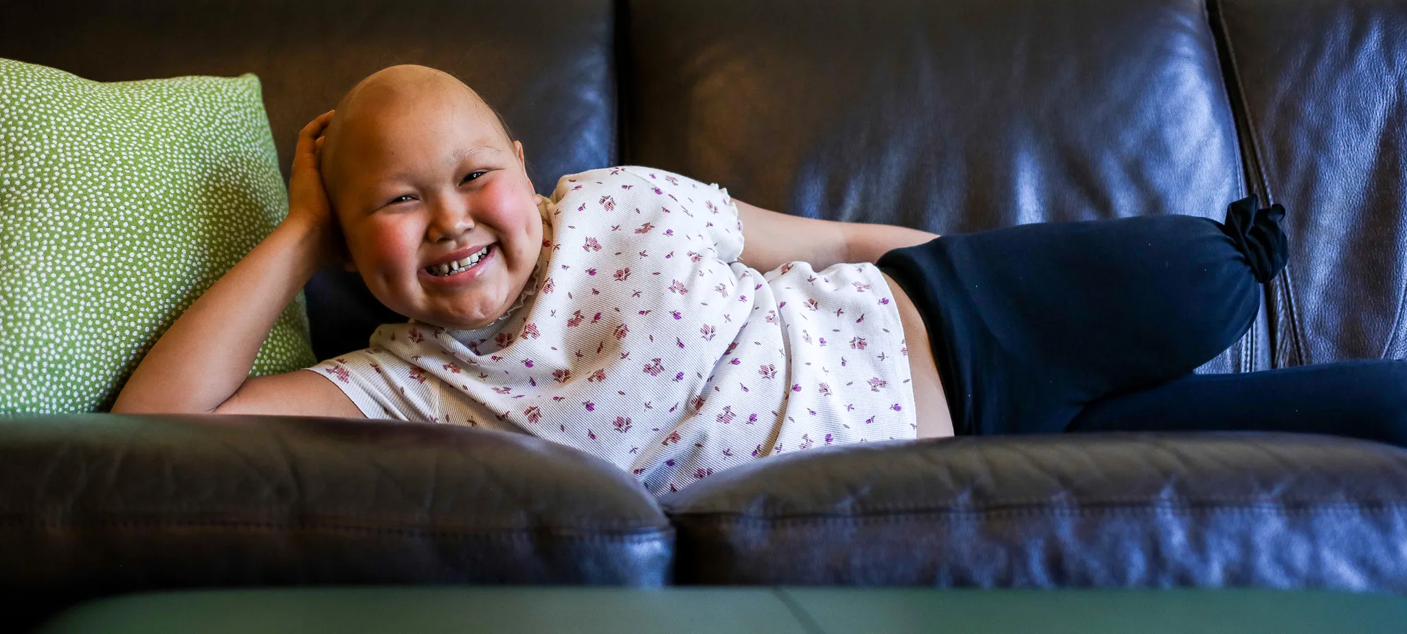 young girl Brystal laying across couch with big smile